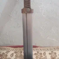 شمشیر با دسته چوبی و نشان فلزی، ظاهر قدیمی و خاص.