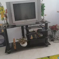تلویزیون سامسونگ و دستگاه ستاپ باکس و میز شیشه ای