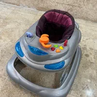 صندلی ماشین همراه با روروک و گهواره کنار تخت