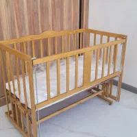 گهواره چوبی و تخت کنار مادر